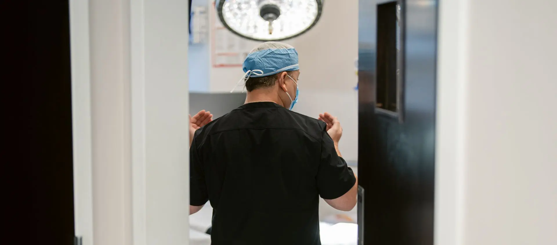 Dr. David Pincus, Plastic Surgeon, wearing black scrubs, walking into surgery suite
