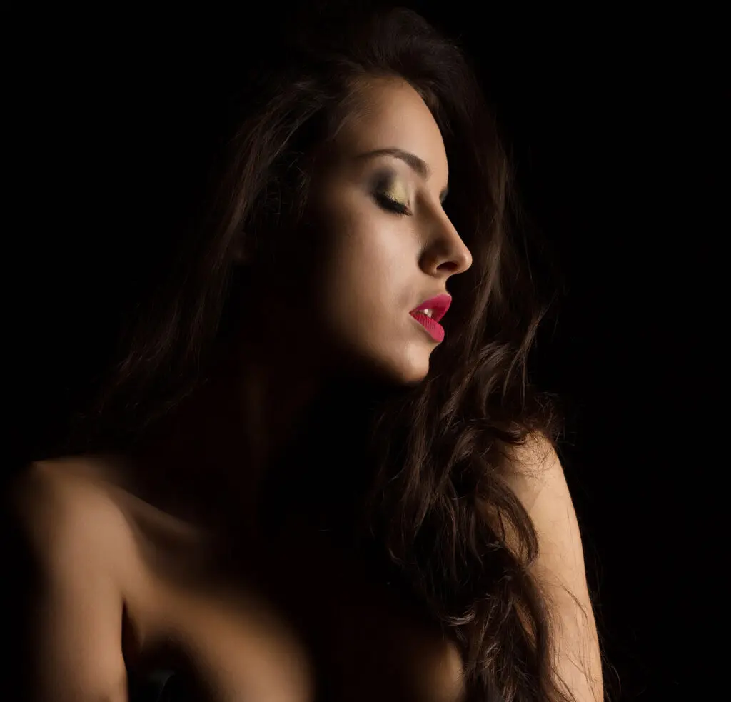 dim headshot of a beautiful woman in red lipstick and long dark hair