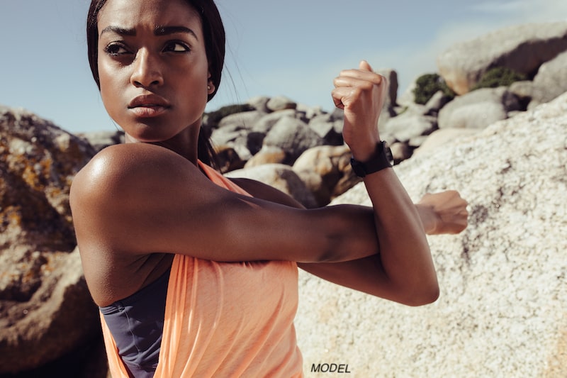 Female runner with a determined facial appearance who is stretching before starting her exercise