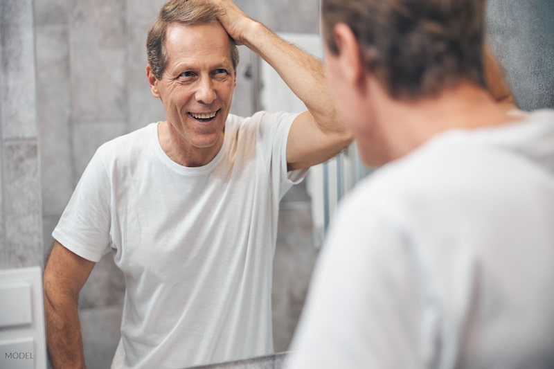 Middle-aged man looking at himself in the mirror and smiling