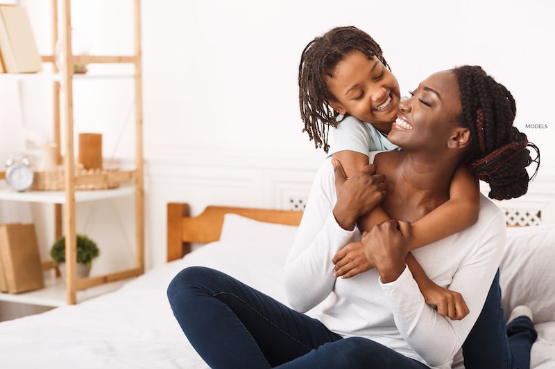 Mother sitting with her daughter on a bed.