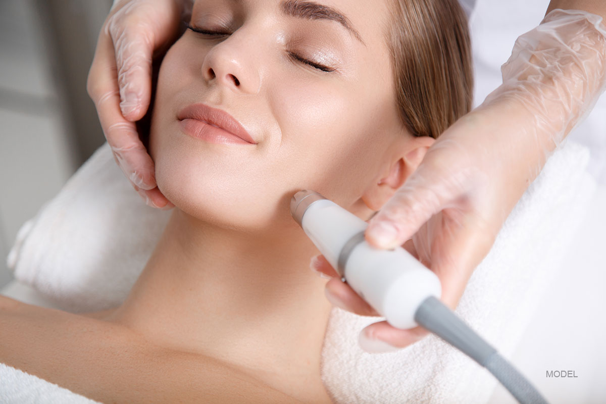 woman looks relaxed while technician administers a laser treatment on her face